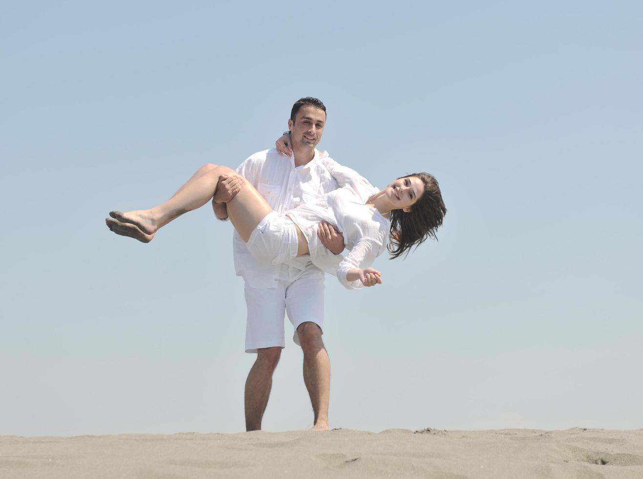 feliz casal jovem se divertir na praia foto