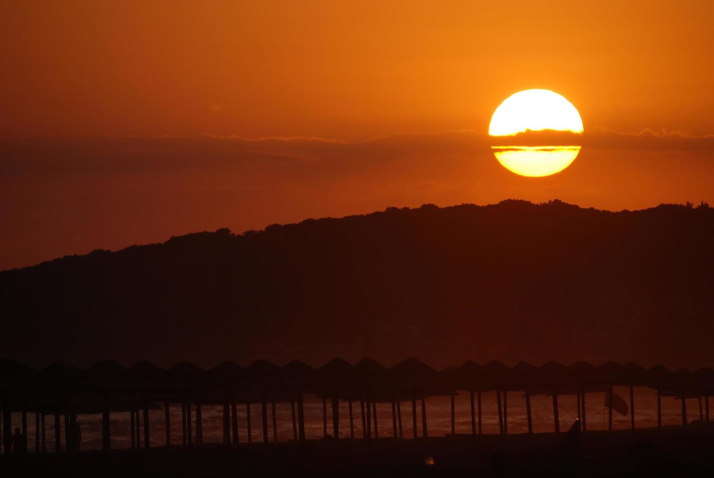 sol na praia com silhueta de guarda-sóis foto