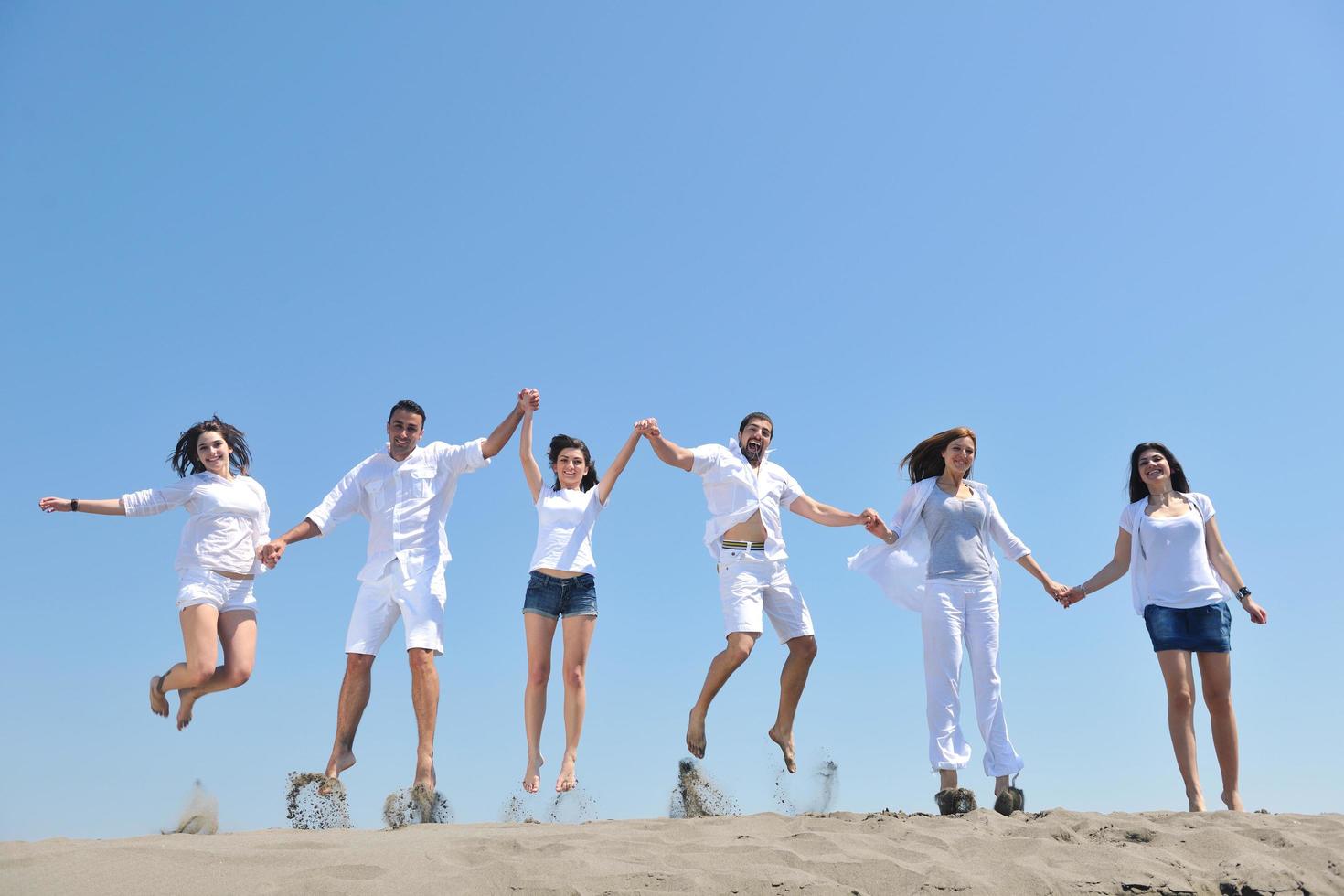 grupo de pessoas felizes se divertir e correr na praia foto