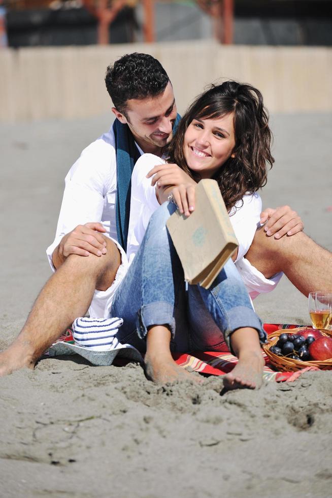 jovem casal desfrutando de piquenique na praia foto