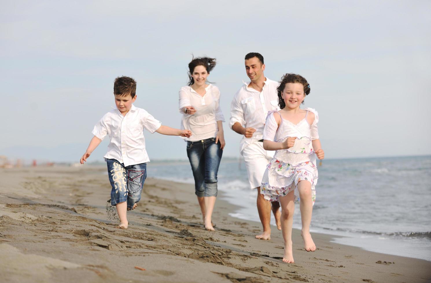 feliz jovem família se divertir na praia foto