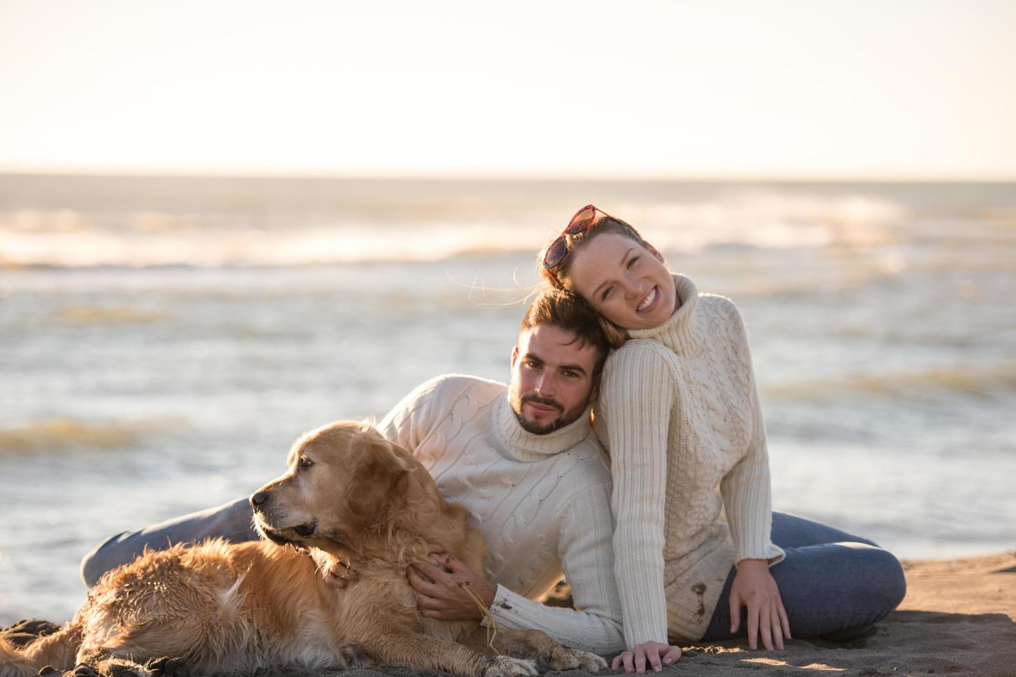 casal com cachorro aproveitando o tempo na praia foto