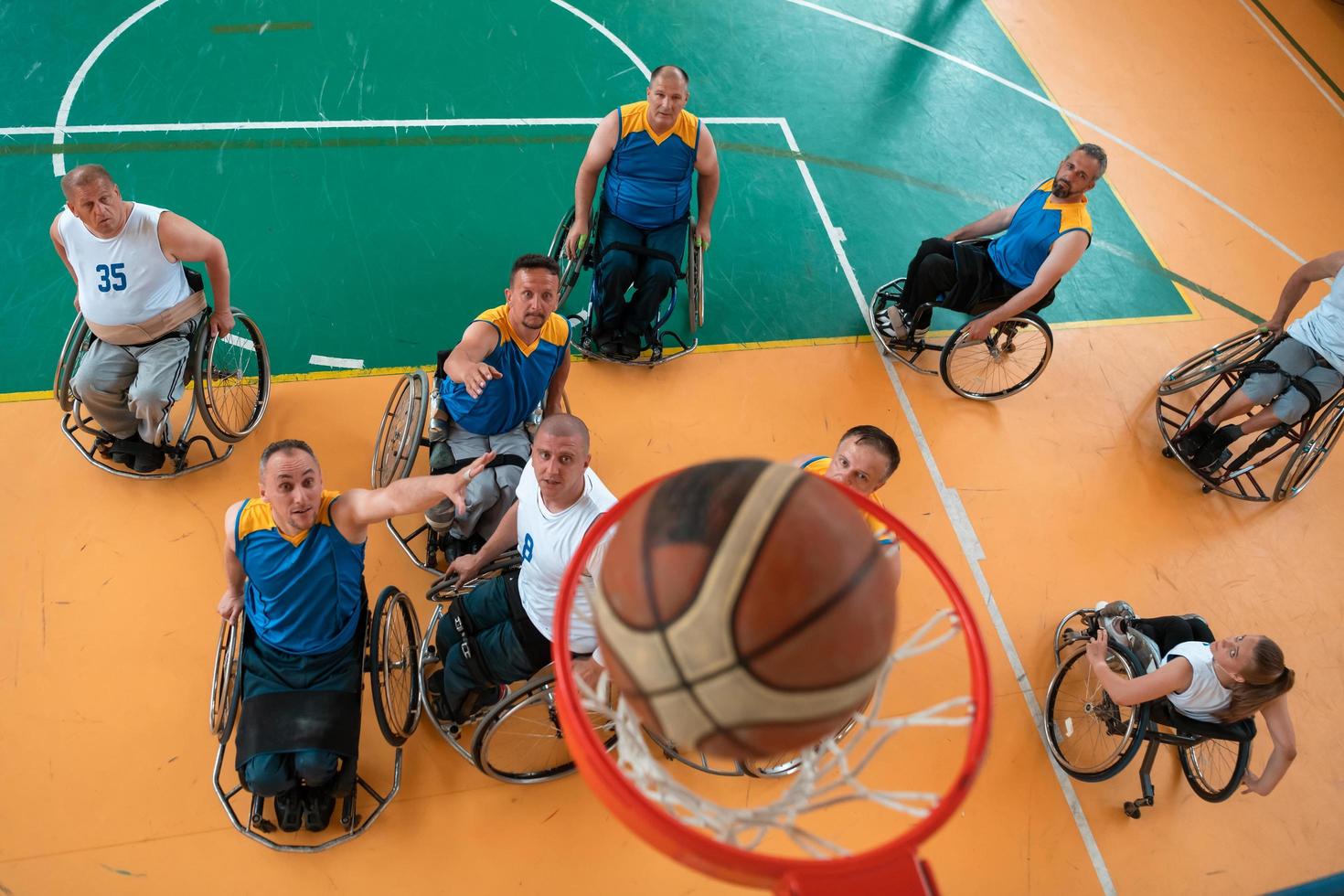 guerra com deficiência ou veteranos de trabalho mistos de raça e idade equipes de basquete em cadeiras de rodas jogando uma partida de treinamento em um ginásio de esportes. conceito de reabilitação e inclusão de pessoas com deficiência. foto