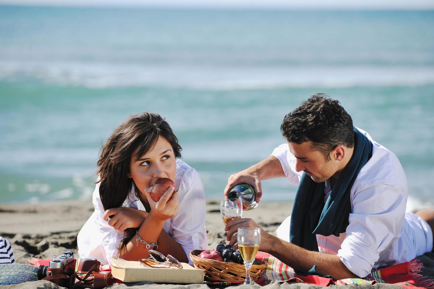 jovem casal desfrutando de piquenique na praia foto