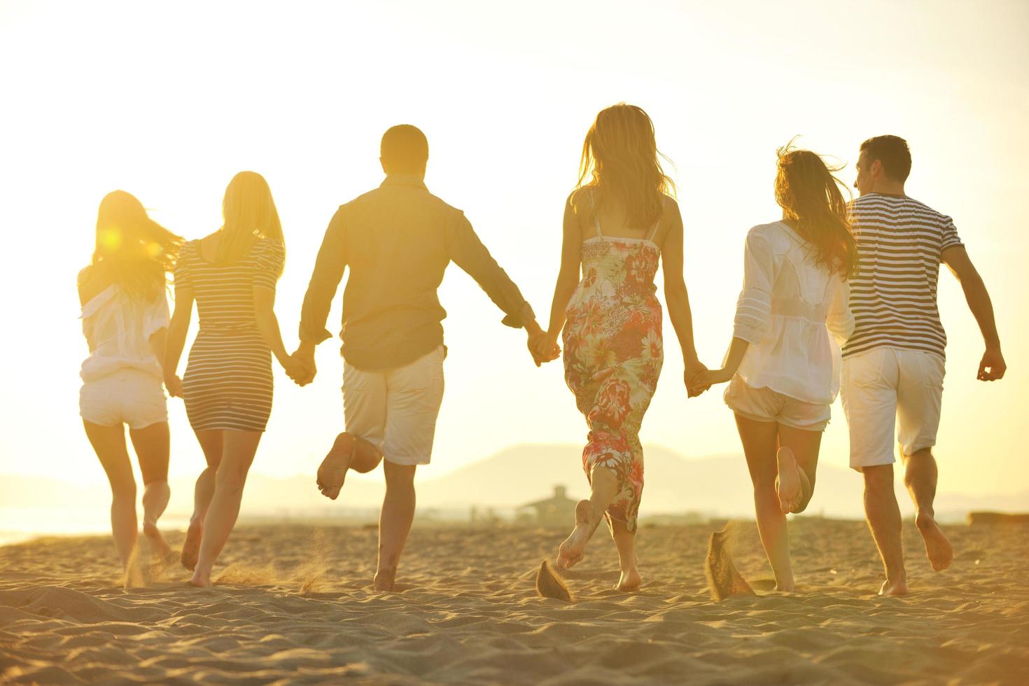 grupo de jovens felizes se divertem na praia foto