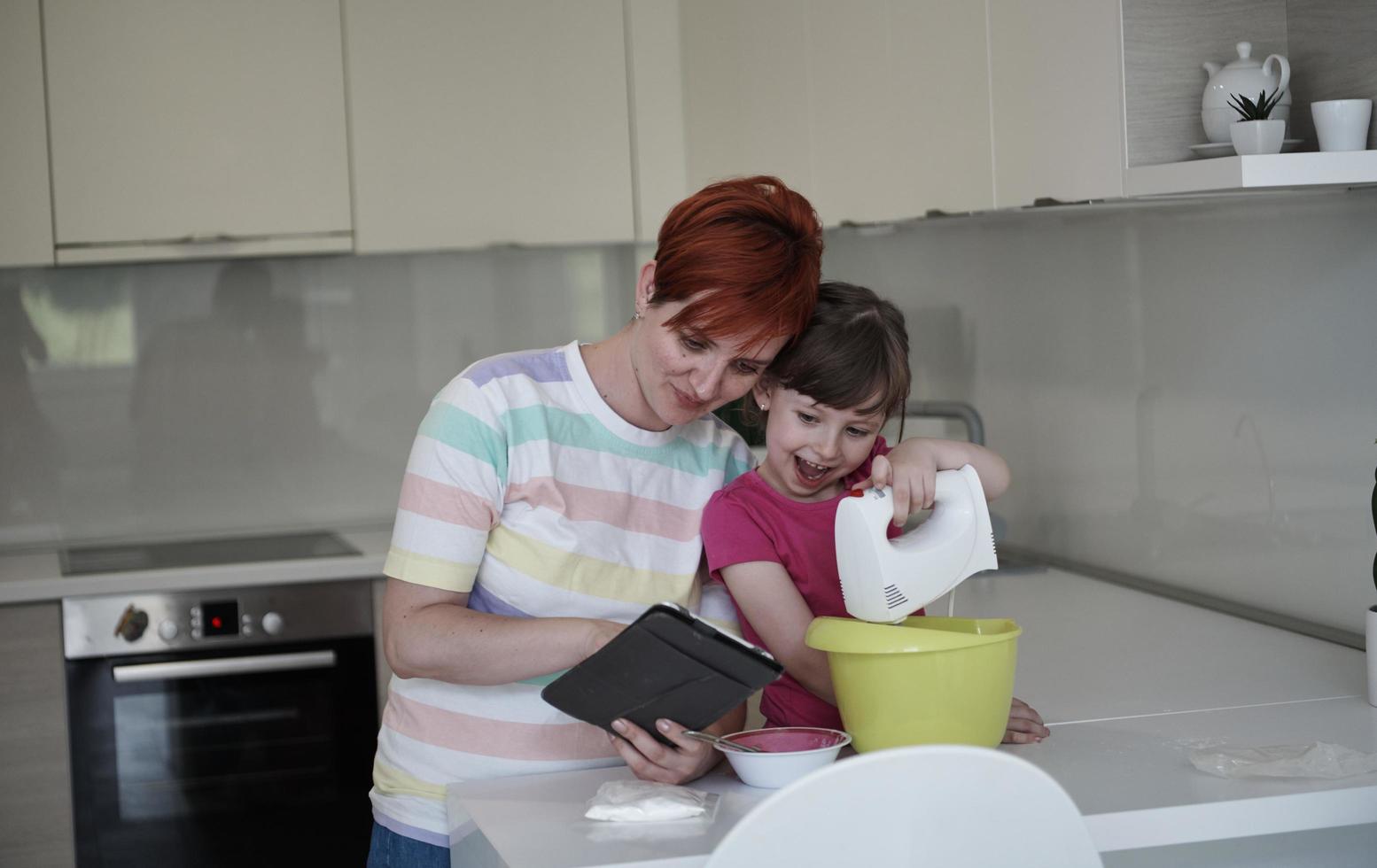 mãe e filha brincando e preparando massa na cozinha. foto