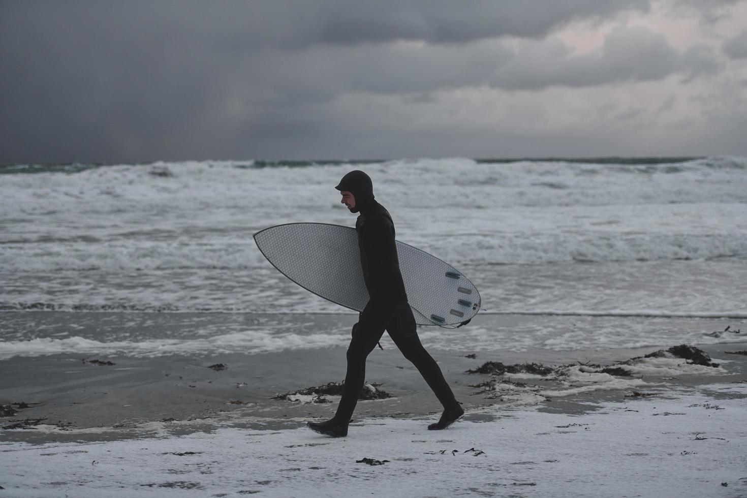 surfista do ártico indo pela praia depois de surfar foto