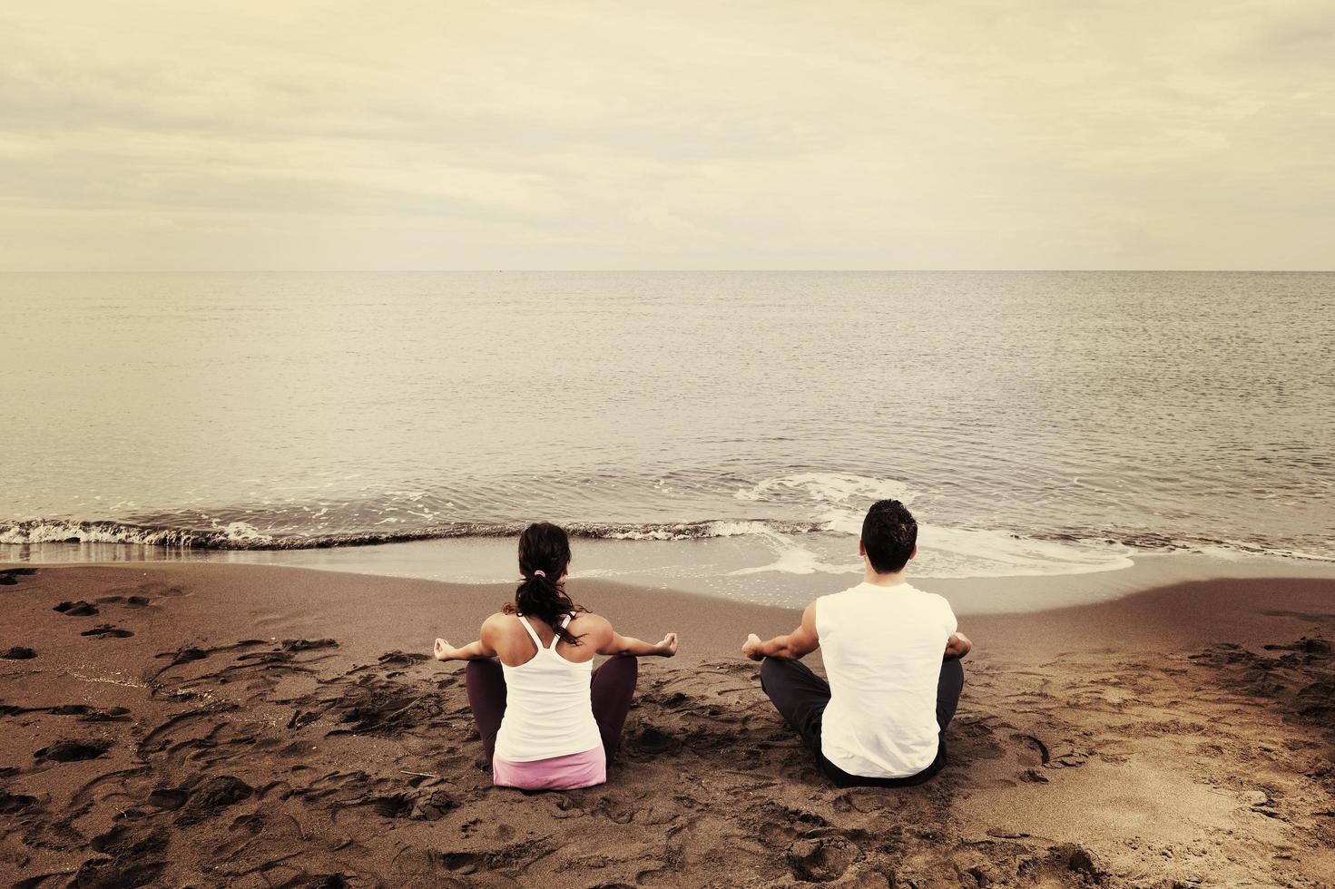 casal ioga praia foto