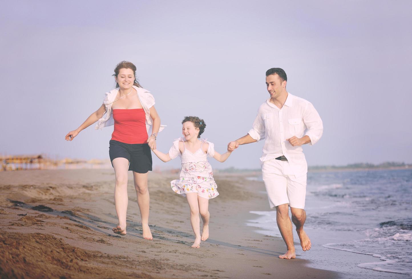 feliz jovem família se divertir na praia foto
