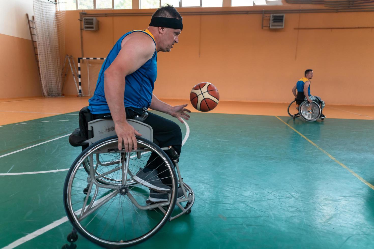 Veteranos de guerra com deficiência equipes de basquete de raça mista e idade em cadeiras de rodas jogando uma partida de treinamento em um ginásio de esportes. conceito de reabilitação e inclusão de pessoas com deficiência foto