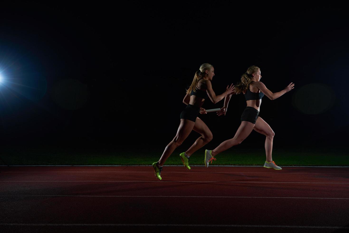 corredores atléticos passando o bastão na corrida de revezamento foto