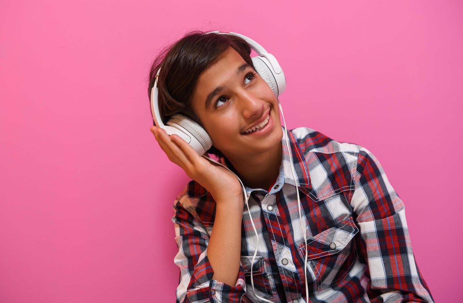 adolescente árabe usando fones de ouvido e ouvindo música fundo rosa foto