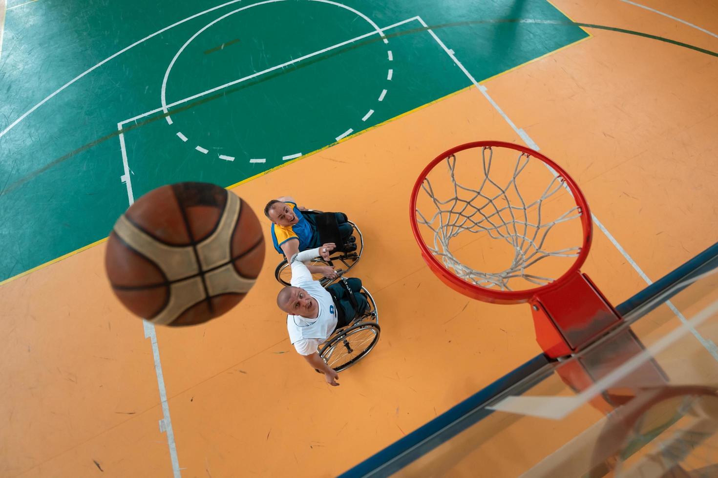 guerra com deficiência ou veteranos de trabalho mistos de raça e idade equipes de basquete em cadeiras de rodas jogando uma partida de treinamento em um ginásio de esportes. conceito de reabilitação e inclusão de pessoas com deficiência. foto