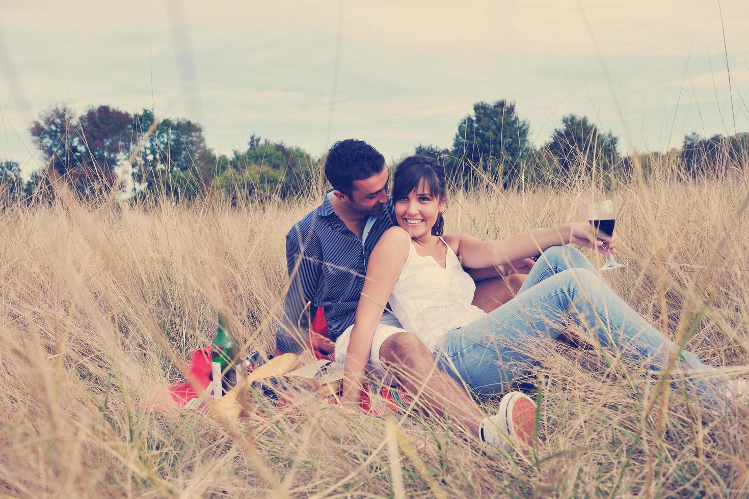 casal feliz desfrutando de piquenique no campo em grama longa foto