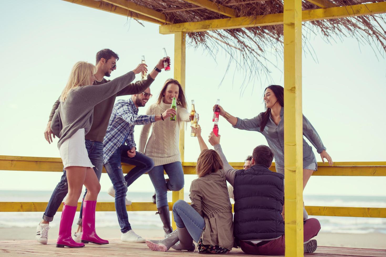 grupo de amigos se divertindo no dia de outono na praia foto