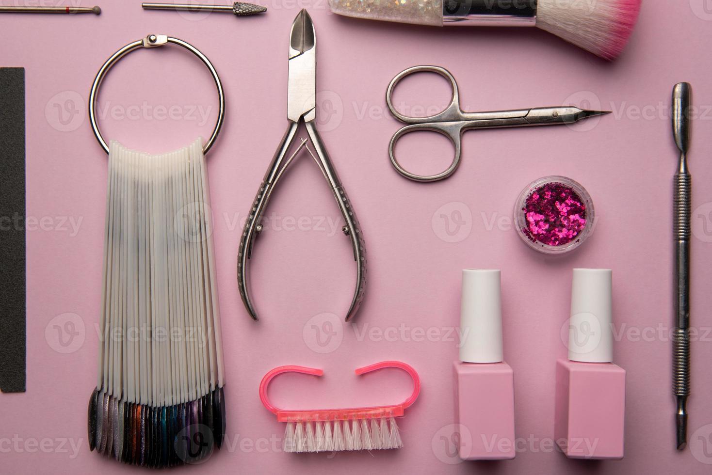 conjunto de ferramentas de manicure e acessórios em um fundo rosa. manicure de hardware, postura plana. foto