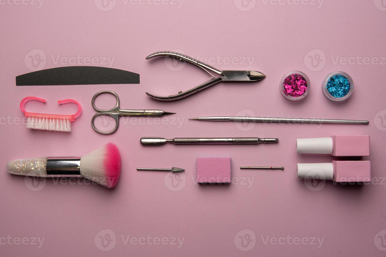 conjunto de ferramentas de manicure e acessórios em um fundo rosa. manicure de hardware, postura plana. foto