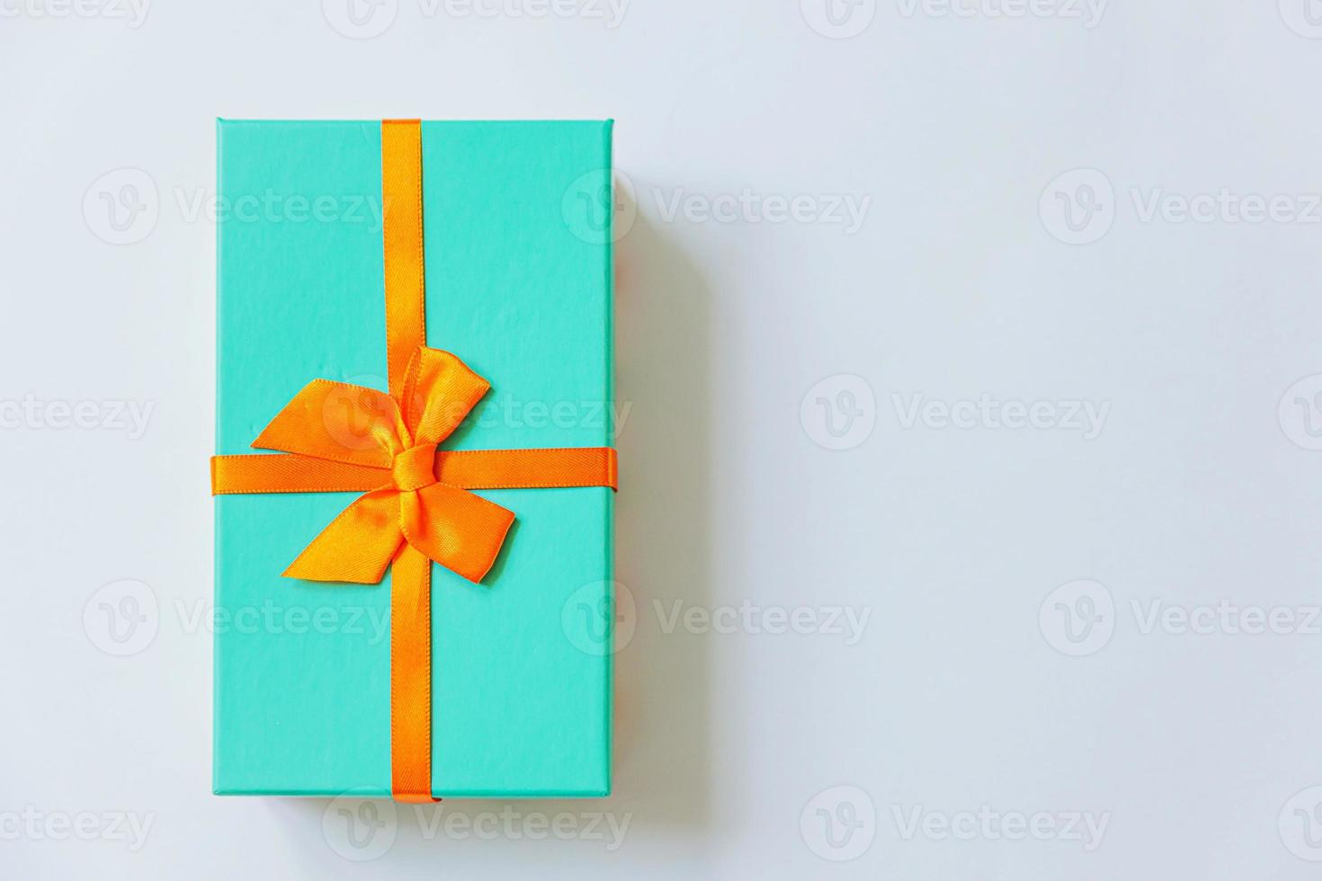 natal ano novo aniversário valentine celebração presente conceito romântico. caixa de presente azul de design simplesmente minimalista com fita laranja isolada no fundo branco. espaço de cópia de vista superior plana leiga. foto