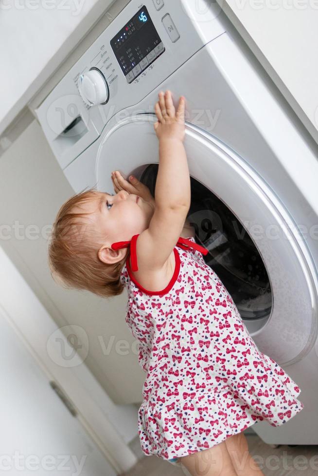 criança com máquina de lavar. menina está ajudando nas tarefas familiares. foto