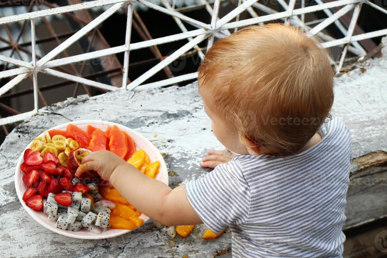 menina está comendo frutas tropicais maduras frescas, vista traseira. foto