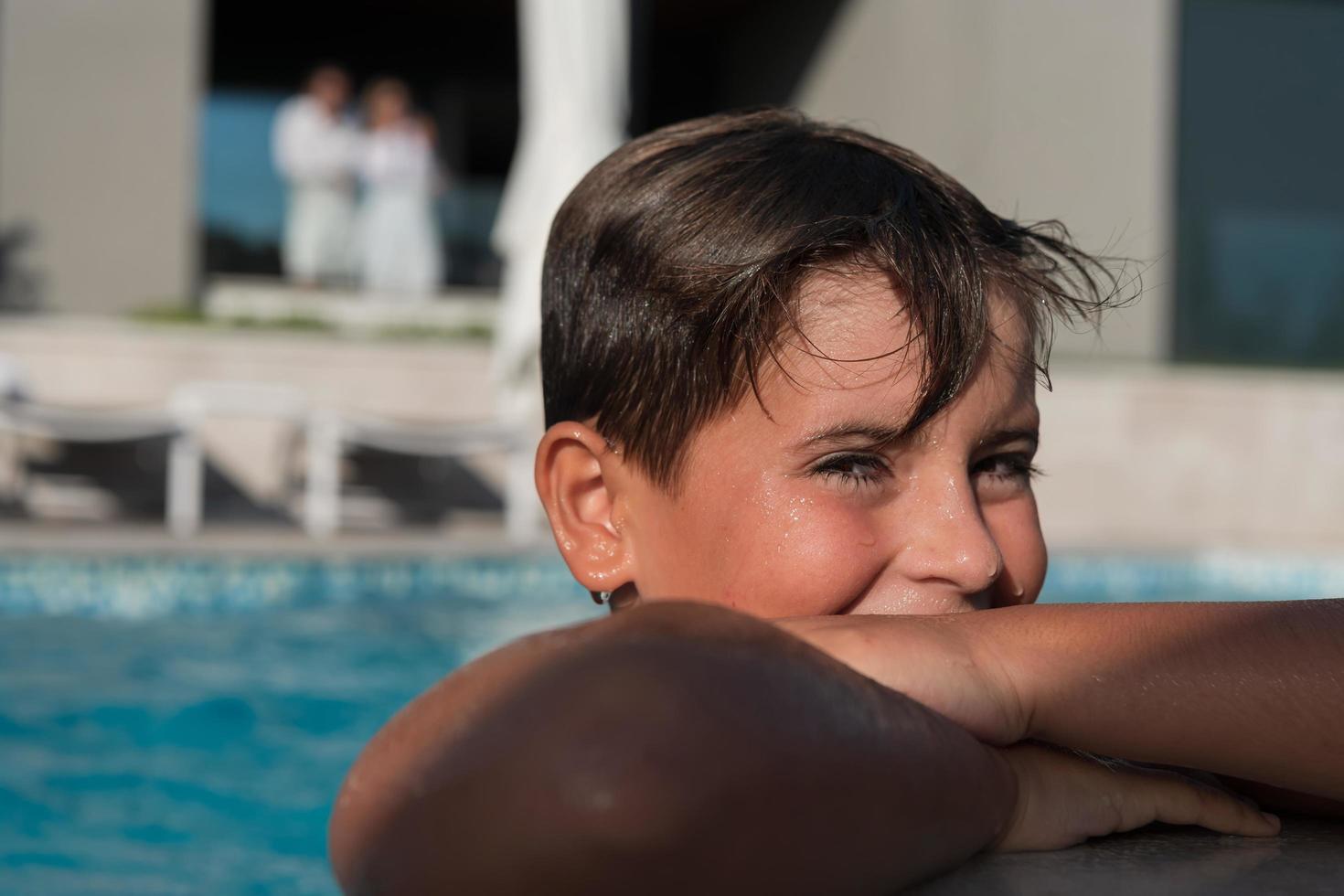 o menino gosta de um dia de verão nadando na piscina. o conceito de férias em família. foco seletivo foto