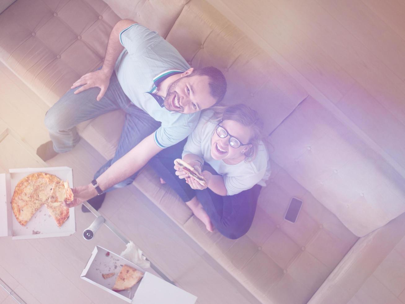 casal comendo pizza em sua casa de luxo foto