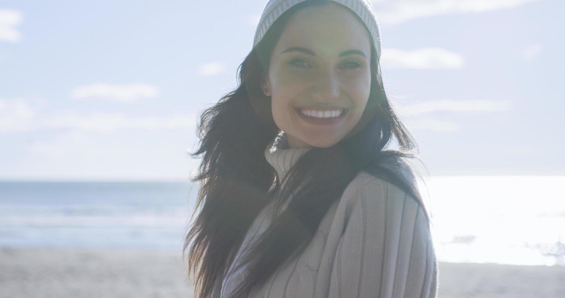 garota com roupas de outono sorrindo na praia foto