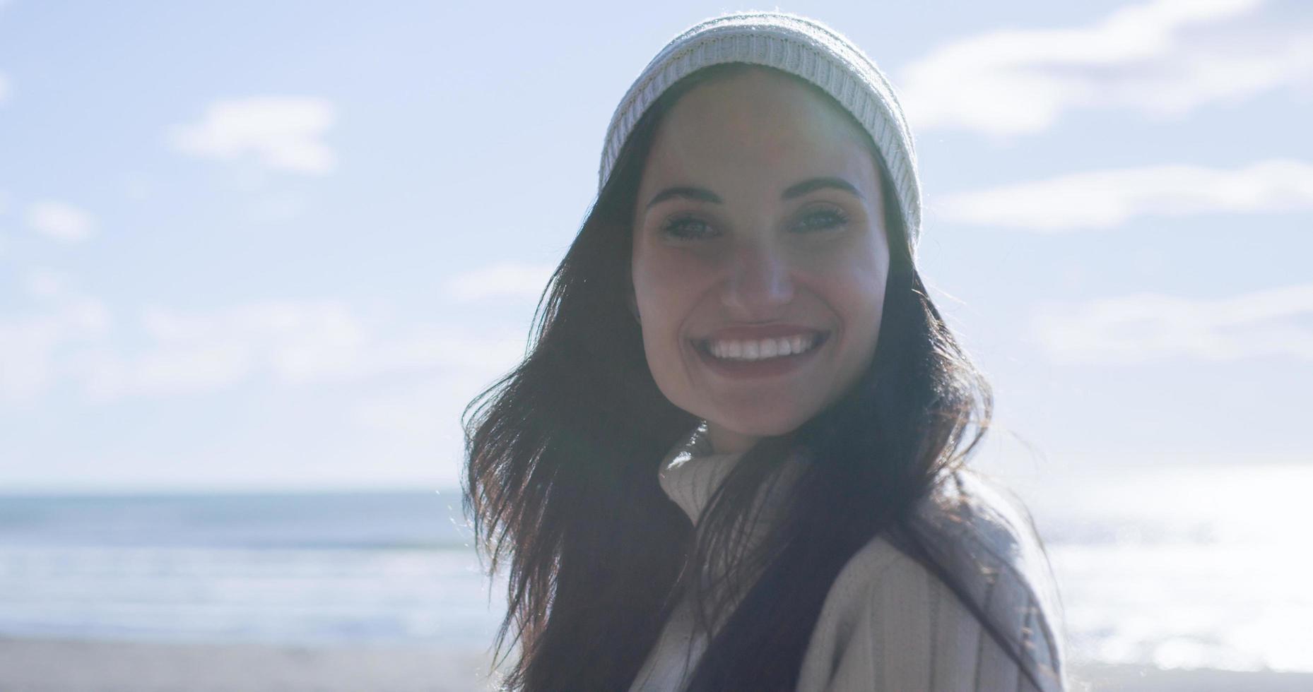 garota com roupas de outono sorrindo na praia foto