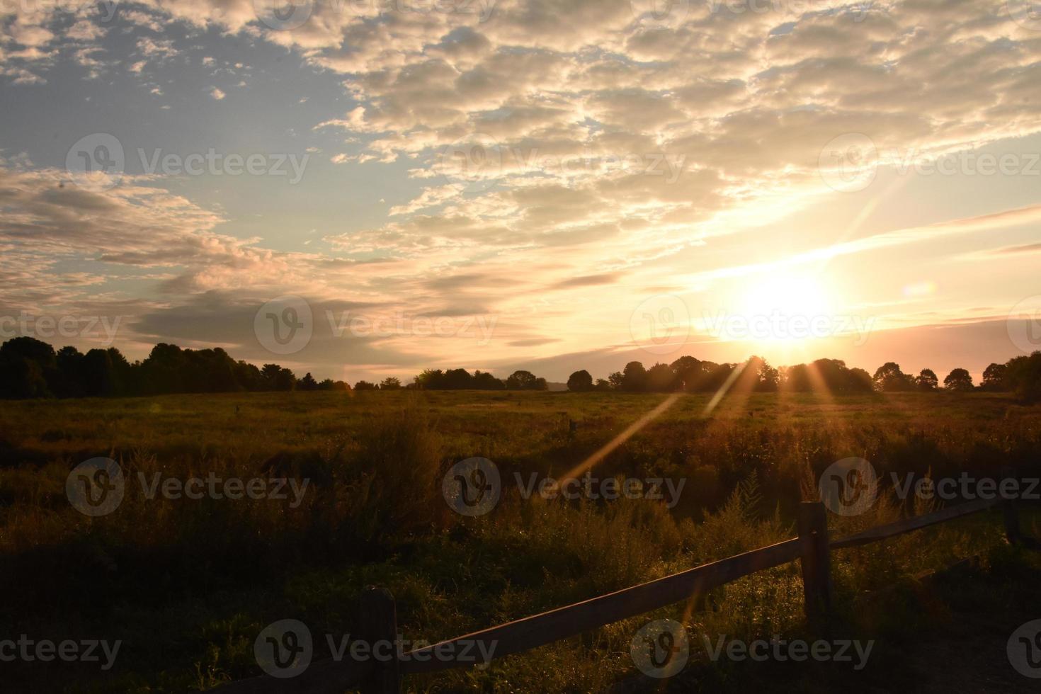 sol nascendo sobre um campo em um dia nublado foto