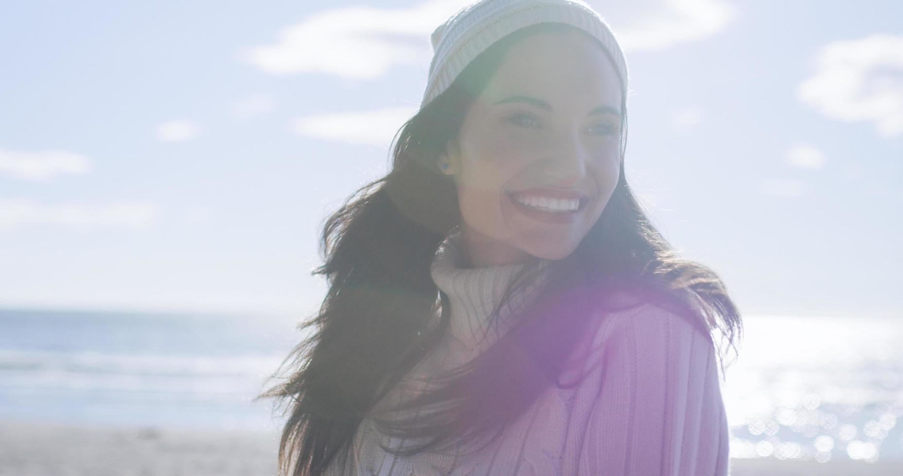 garota com roupas de outono sorrindo na praia foto