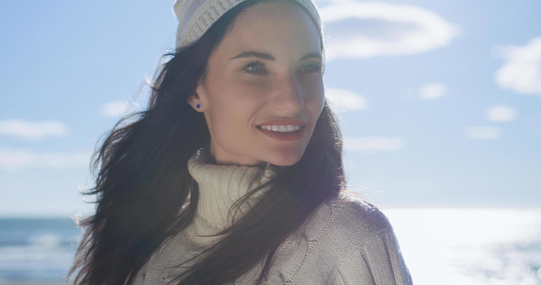 garota com roupas de outono sorrindo na praia foto