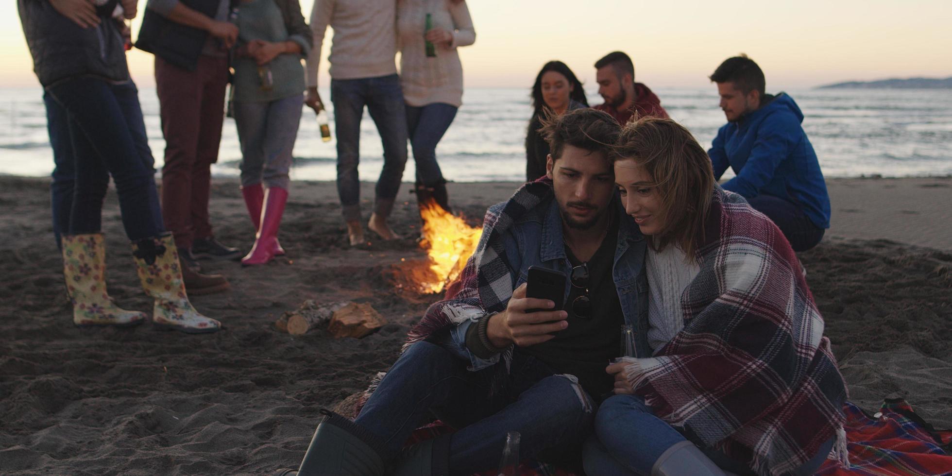 casal curtindo fogueira com amigos na praia foto