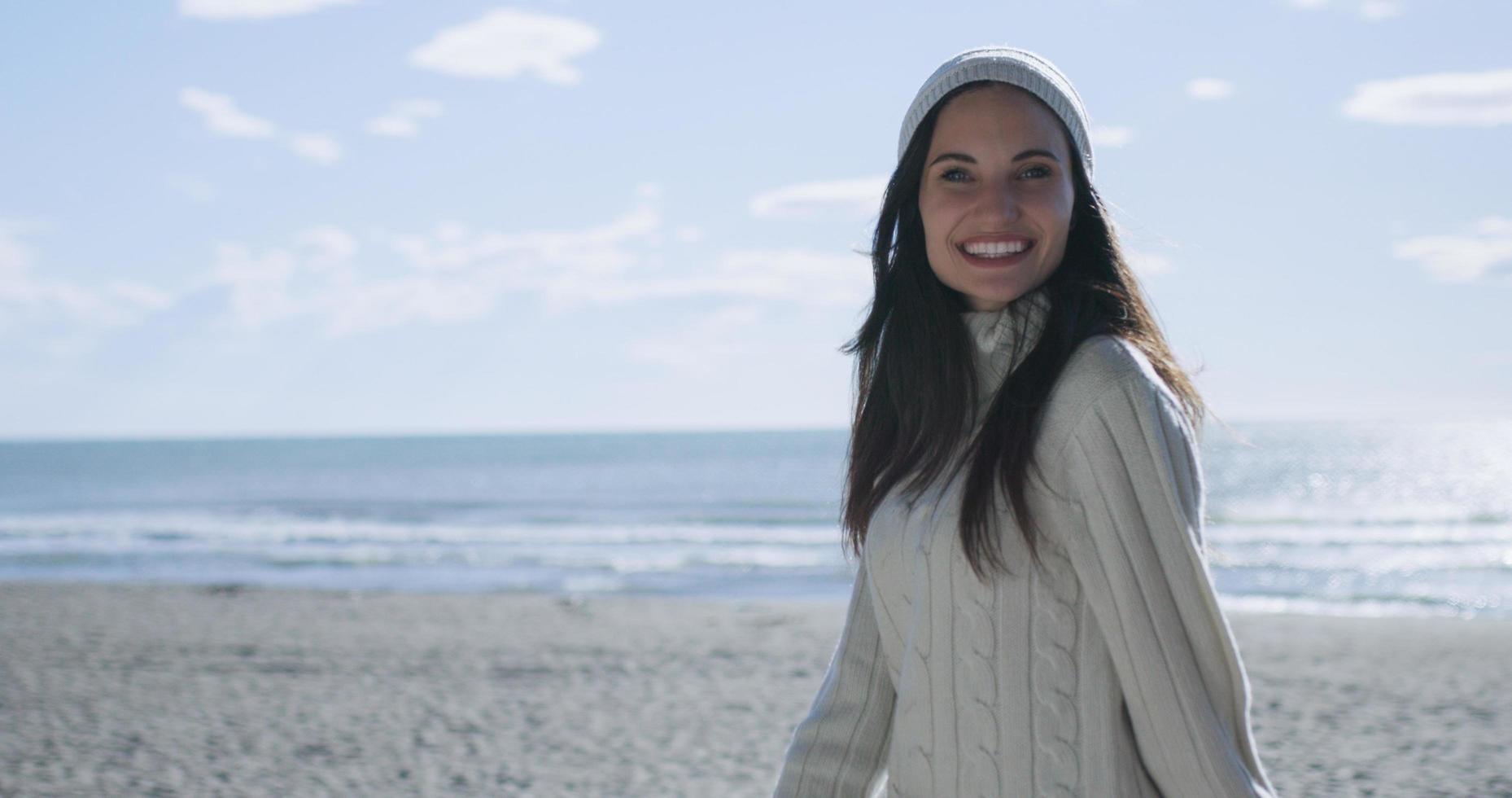 garota com roupas de outono sorrindo na praia foto