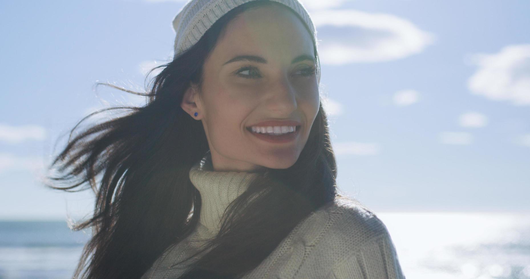 garota com roupas de outono sorrindo na praia foto