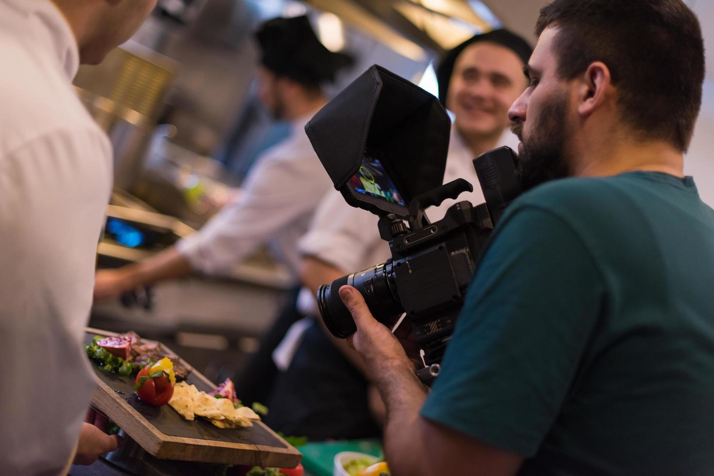 cinegrafista gravando enquanto cozinheiros e chefs de equipe preparam a refeição foto