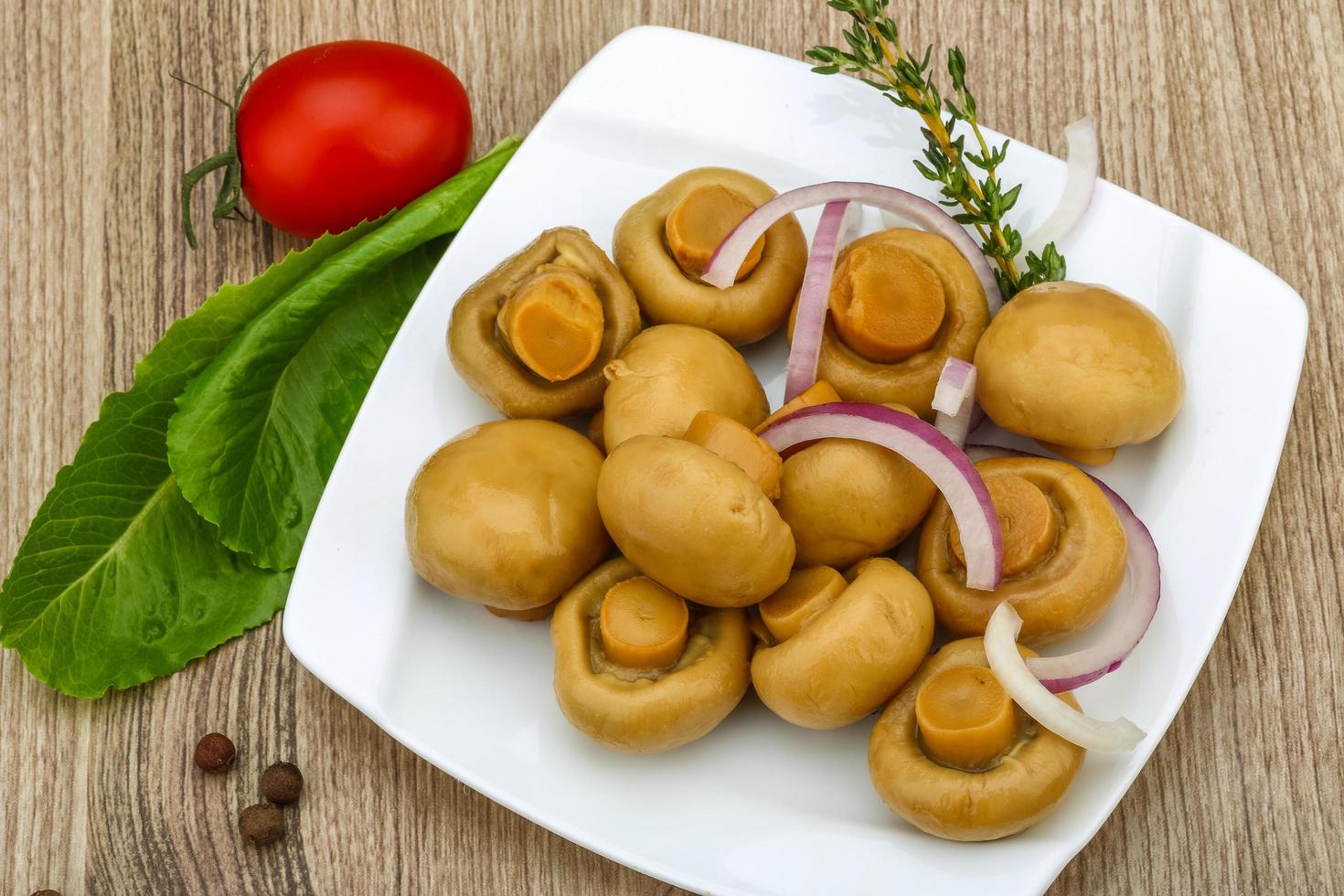 champignon em conserva no prato e fundo de madeira foto