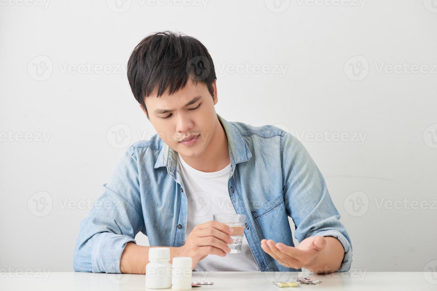 homem tomando seus comprimidos no sofá da sala foto