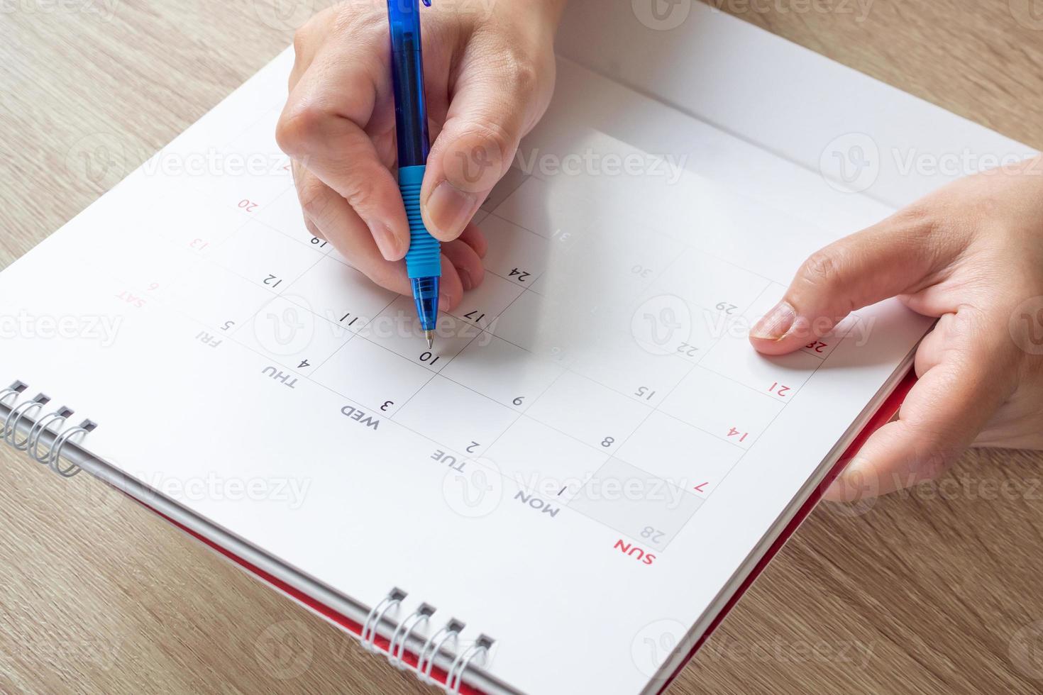 mão de mulher com caneta escrevendo na data do calendário conceito de reunião de planejamento de negócios foto