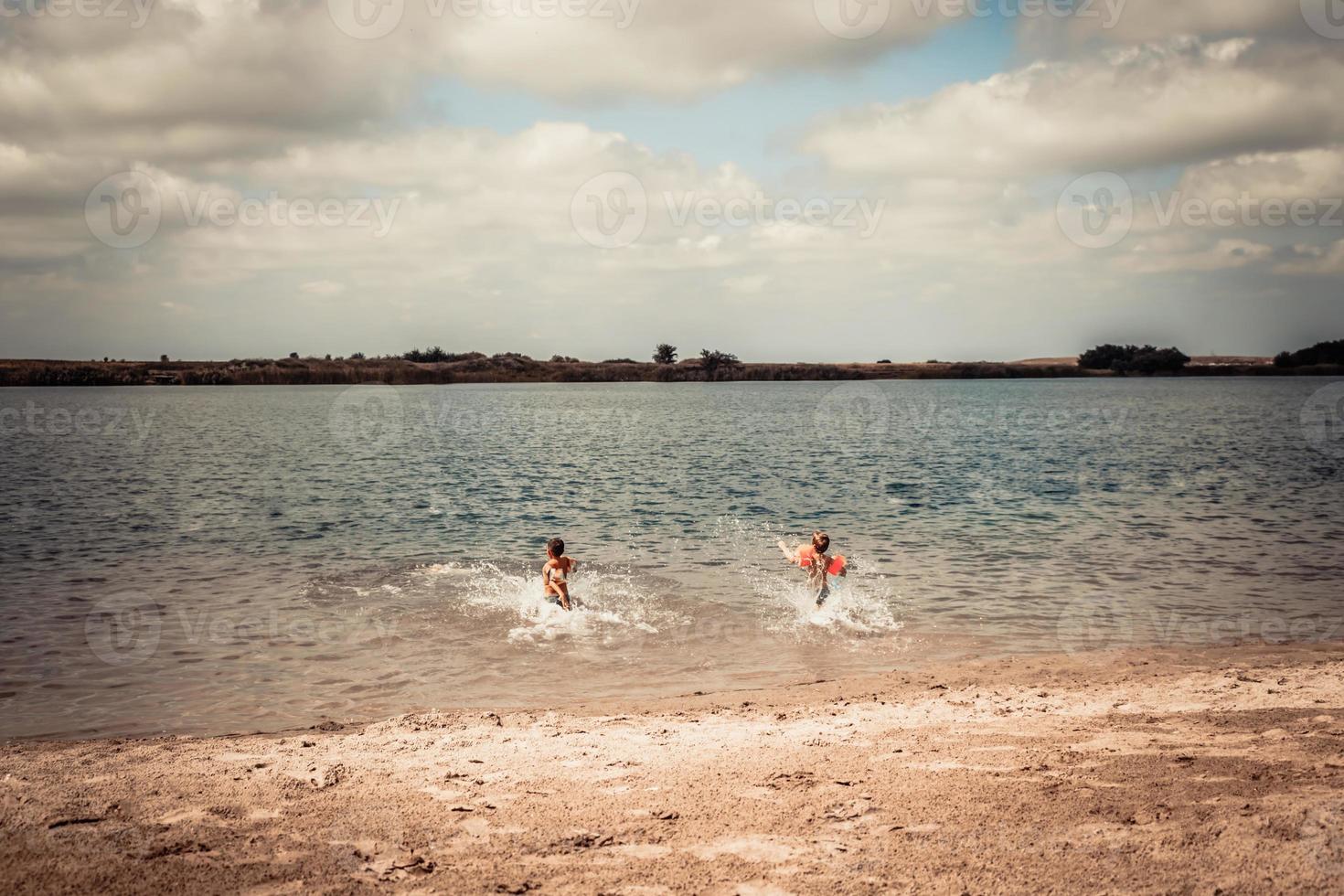 meninos despreocupados correndo na água na praia. foto