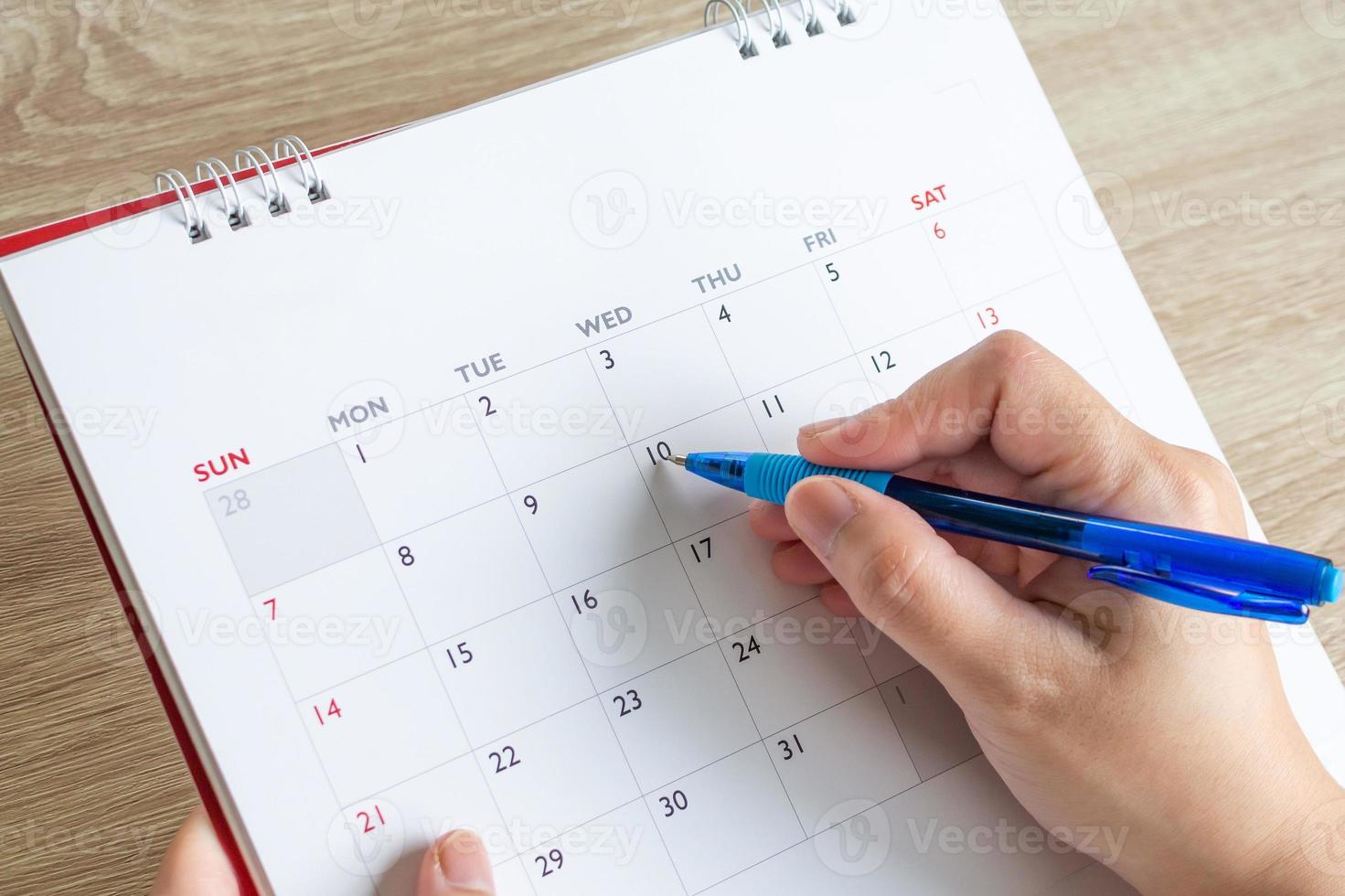 mão de mulher com caneta escrevendo na data do calendário conceito de reunião de planejamento de negócios foto