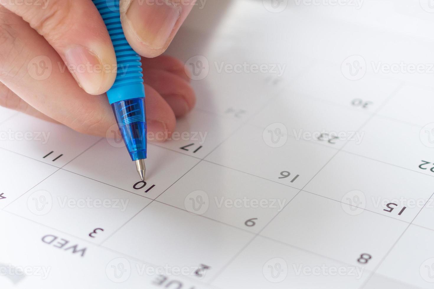 mão de mulher com caneta escrevendo na data do calendário conceito de reunião de planejamento de negócios foto
