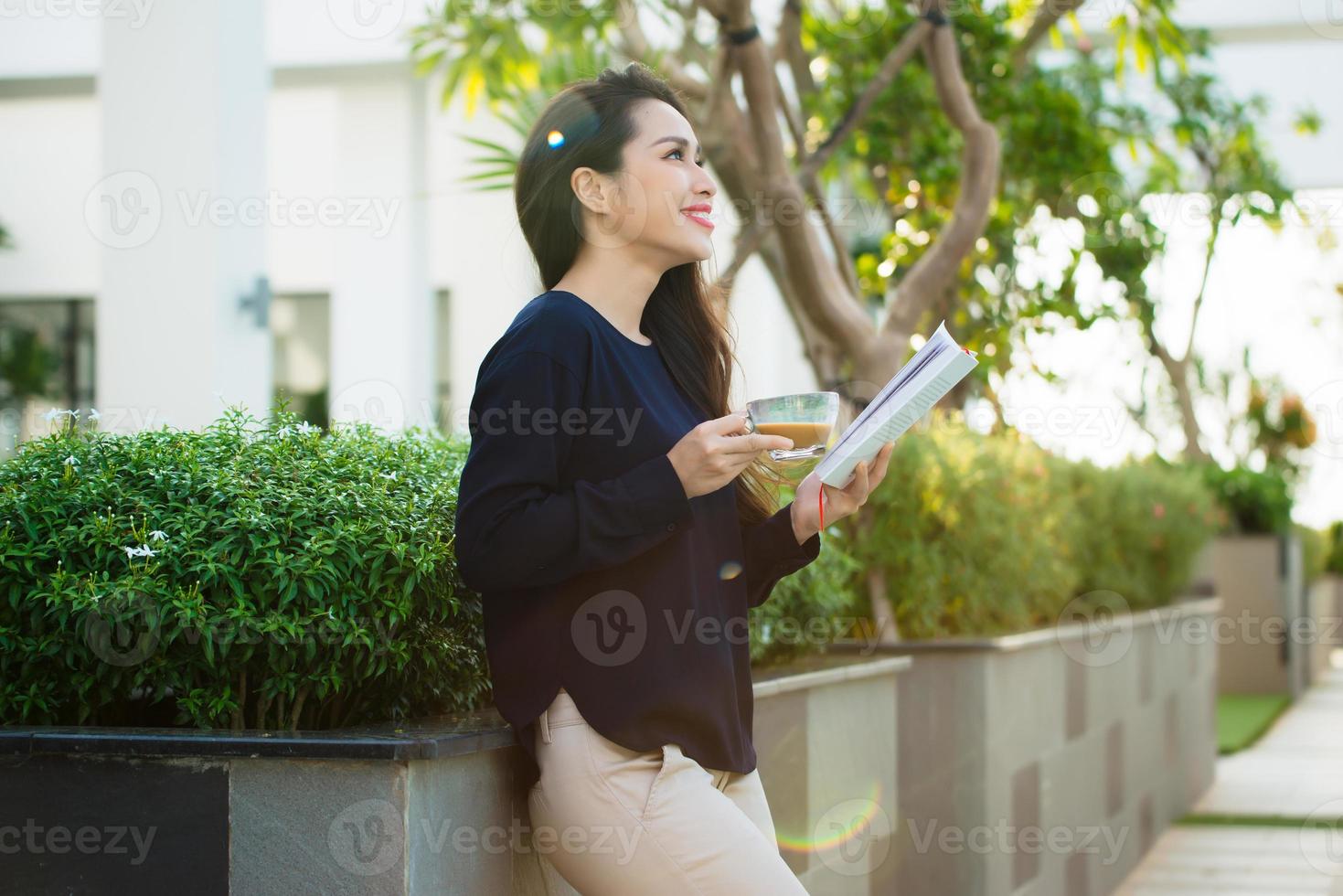 jovem feliz segurando livro apaixonado por literatura analisando romance durante o tempo de lazer no terraço do café do campus em dia ensolarado. foto