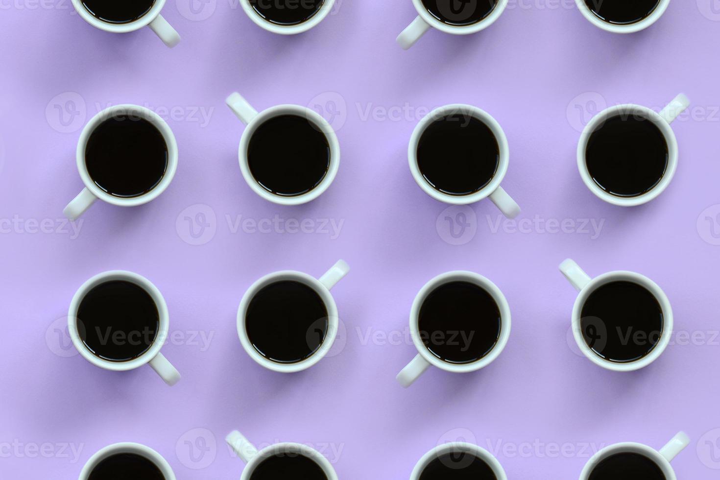 muitos pequenos copos de café branco sobre fundo de textura de papel de cor violeta pastel de moda em conceito mínimo foto