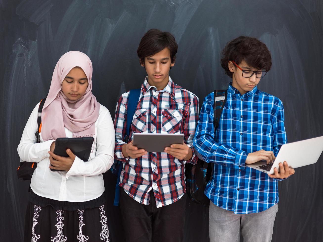 adolescentes árabes modernos usam smartphone, tablet e latpop para estudar durante as aulas online devido à pandemia do vírus corona foto