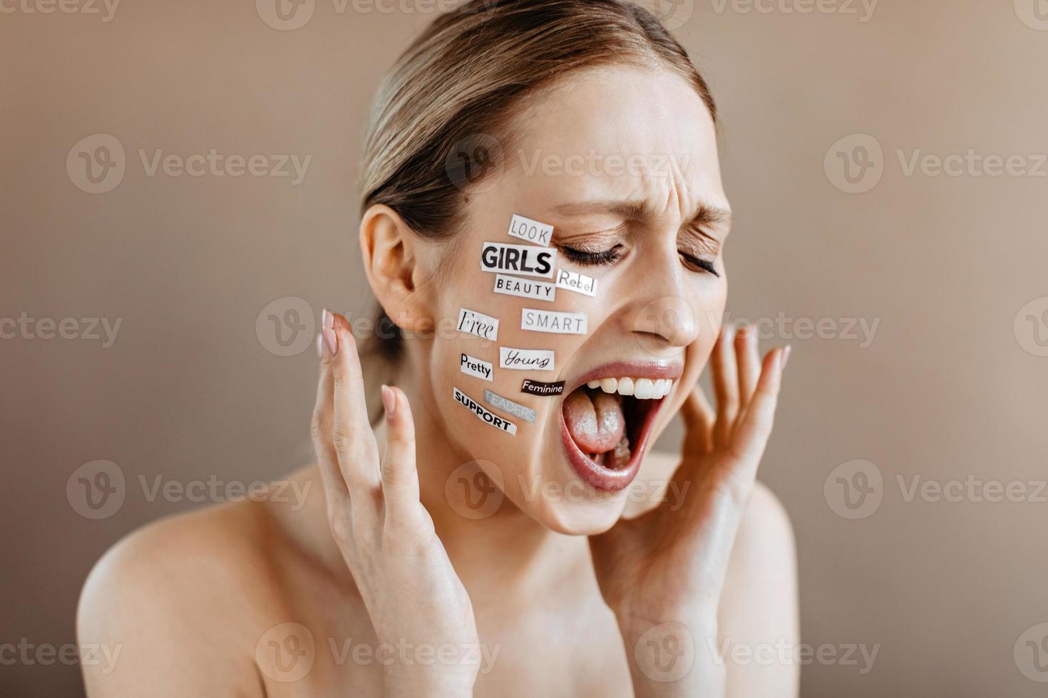 mulher grita e não quer ouvir ninguém. menina com palavras no rosto posando em bege backgr foto