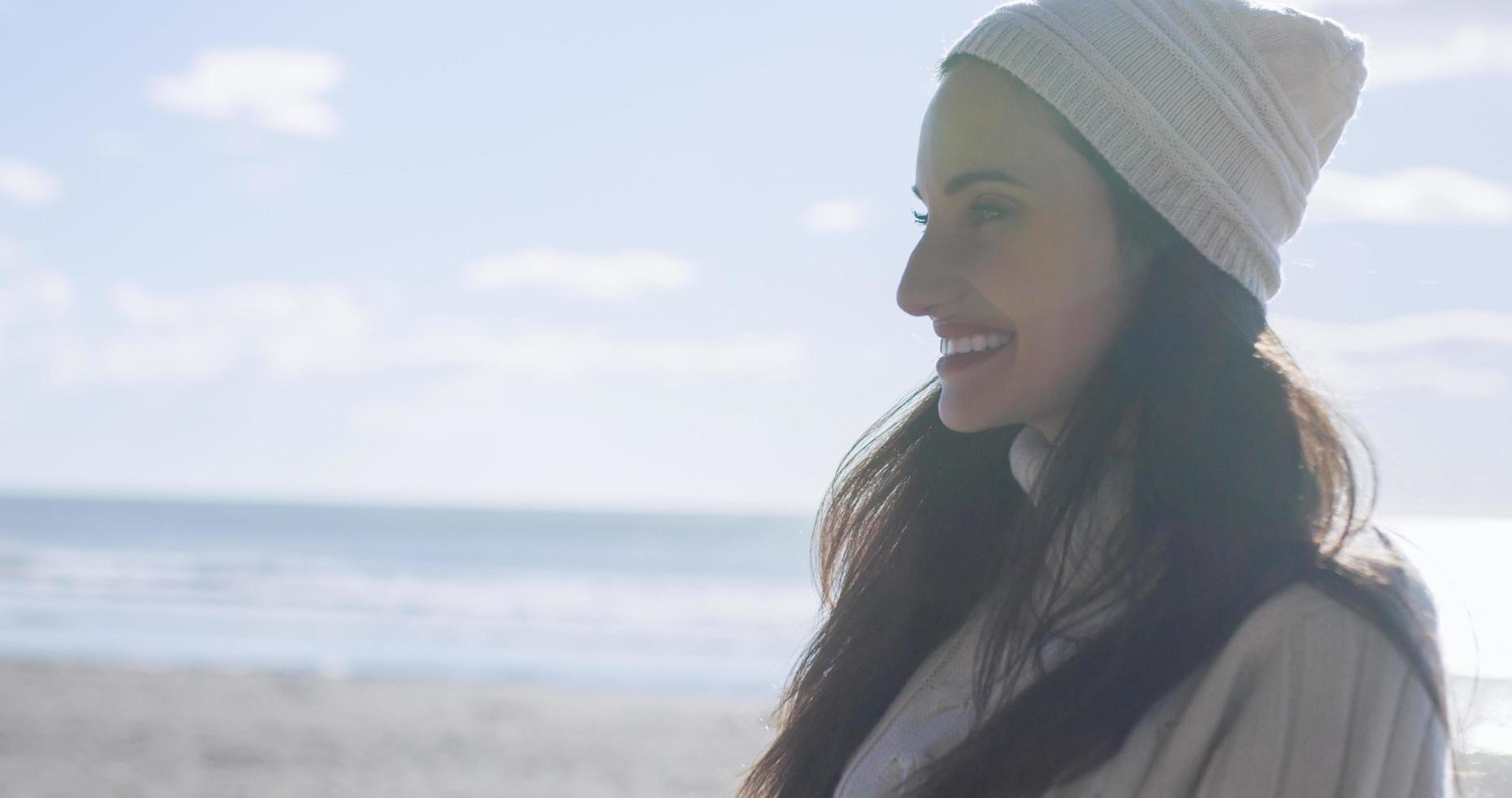 garota com roupas de outono sorrindo na praia foto