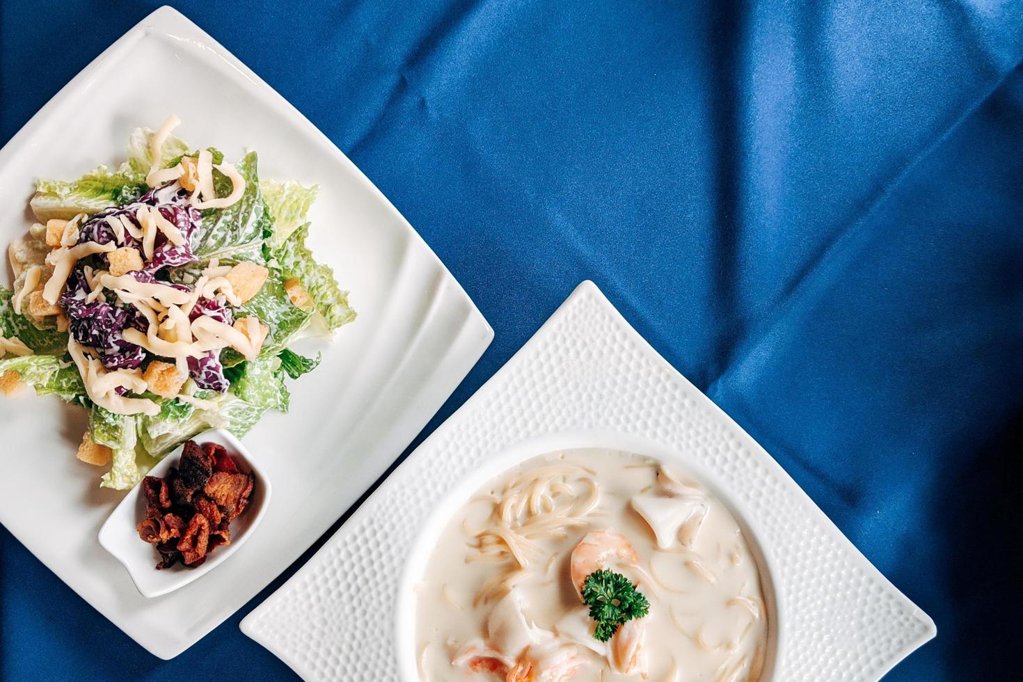 salada cesar e espaguete de frutos do mar plana lay. mesa de vista superior de comida italiana. foto