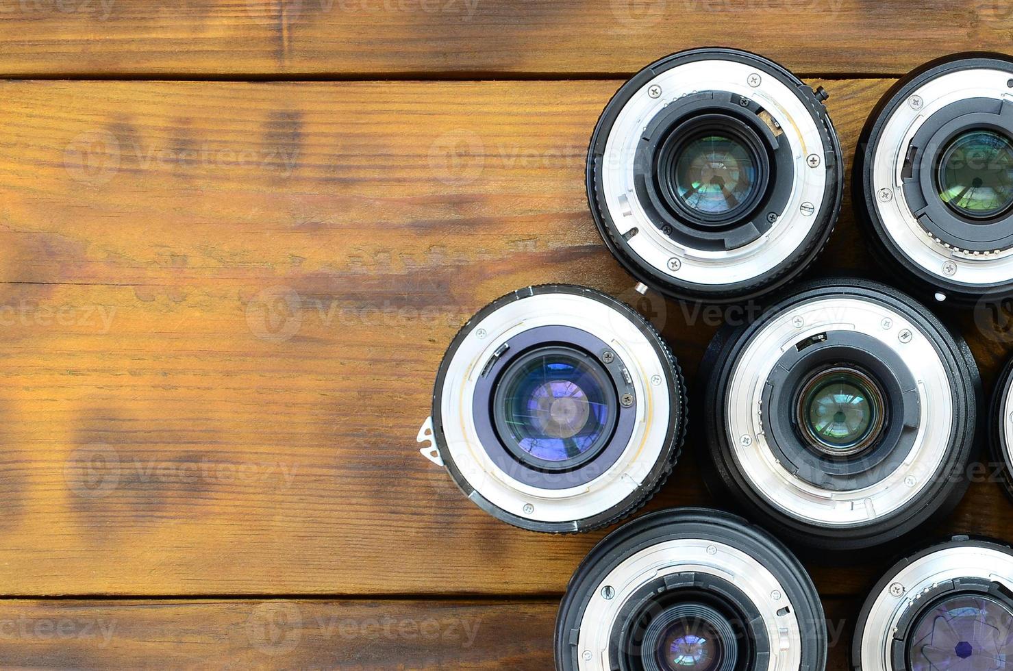 várias lentes fotográficas estão em um fundo de madeira marrom. espaço para texto foto