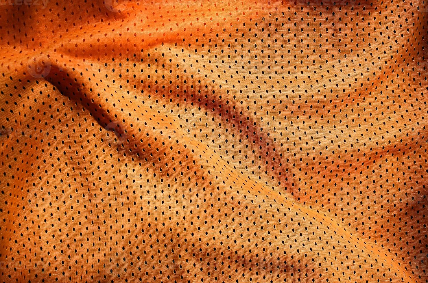 fundo de textura de tecido de vestuário esporte laranja. vista superior da superfície têxtil de pano laranja. camisa de basquete brilhante. espaço de texto foto