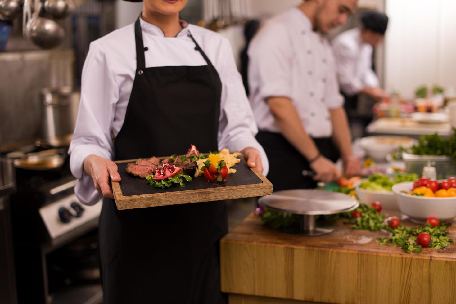 chef feminino segurando o prato de bife foto